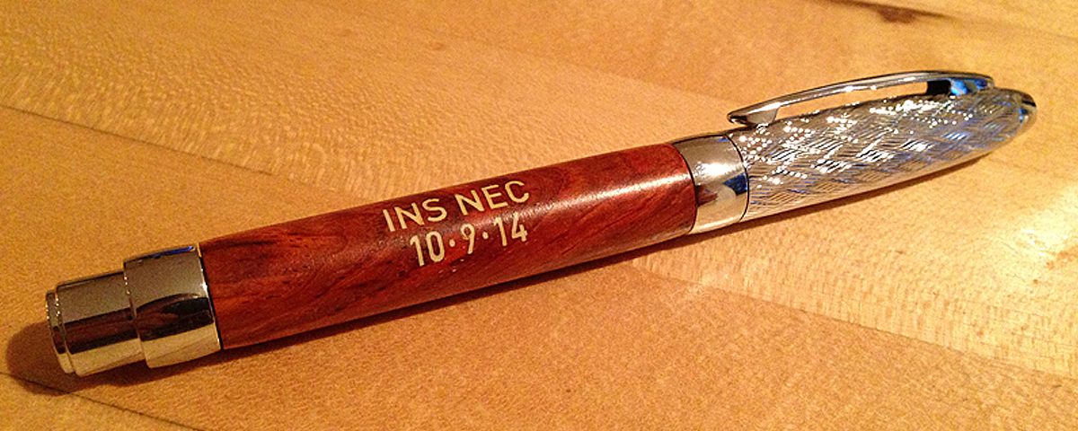 Custom rosewood pen with engraving and color filled letters.